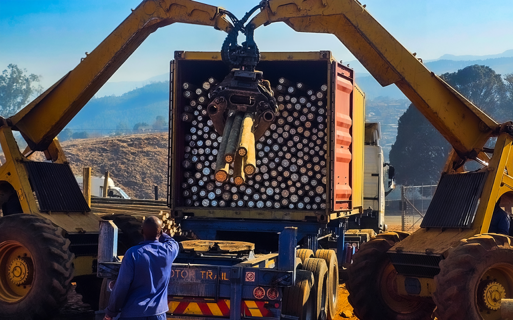Two bells working together to load poles into a container for export
